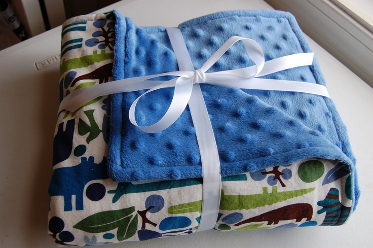 two blue and green baby blankets wrapped in white ribbon on top of a window sill