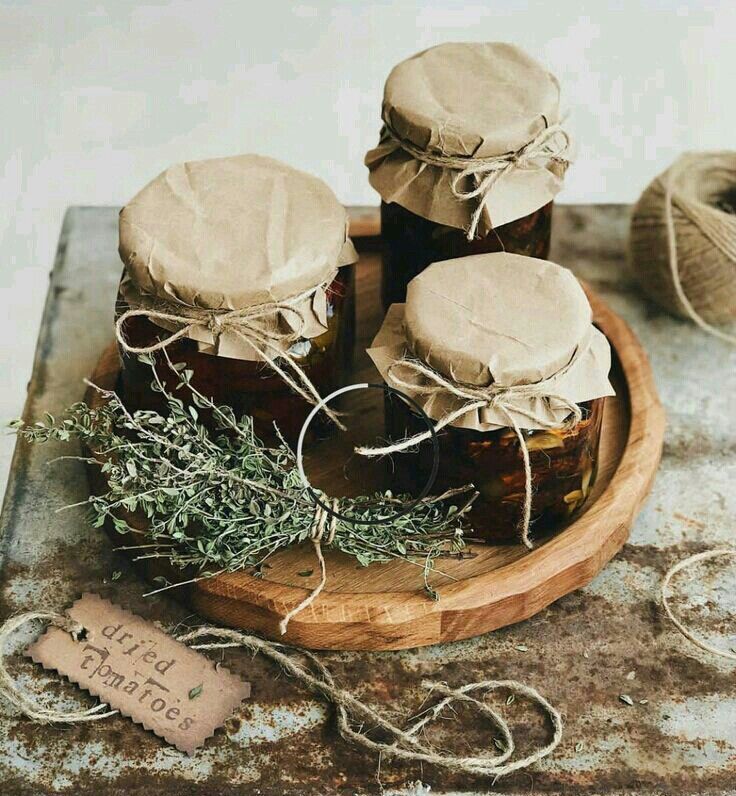 three jars filled with honey sitting on top of a wooden tray next to twine string