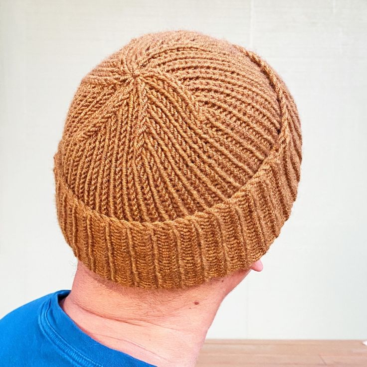 a man wearing a brown knitted hat on top of a wooden table