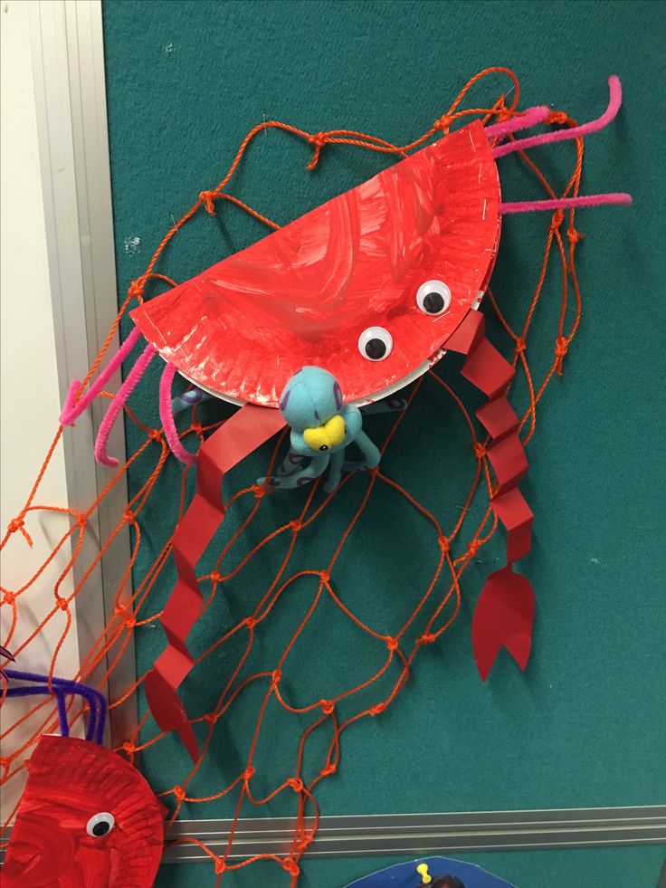 a paper plate crab on the side of a wall with other items in front of it