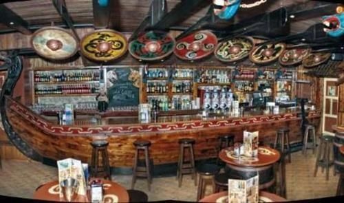 the inside of a restaurant with many wooden tables and stools