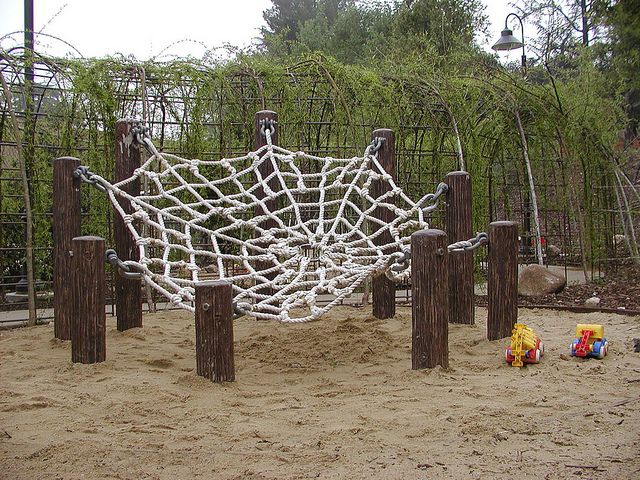 an outdoor play area with wooden posts and ropes