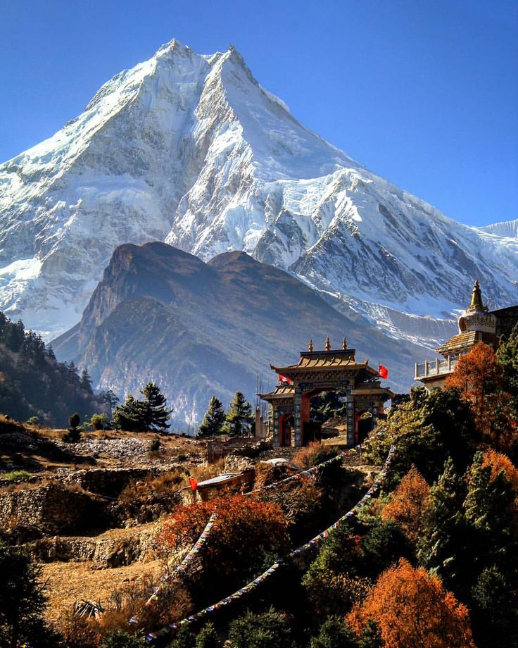 the mountain is covered in snow and has a pagoda on it's side, surrounded by trees