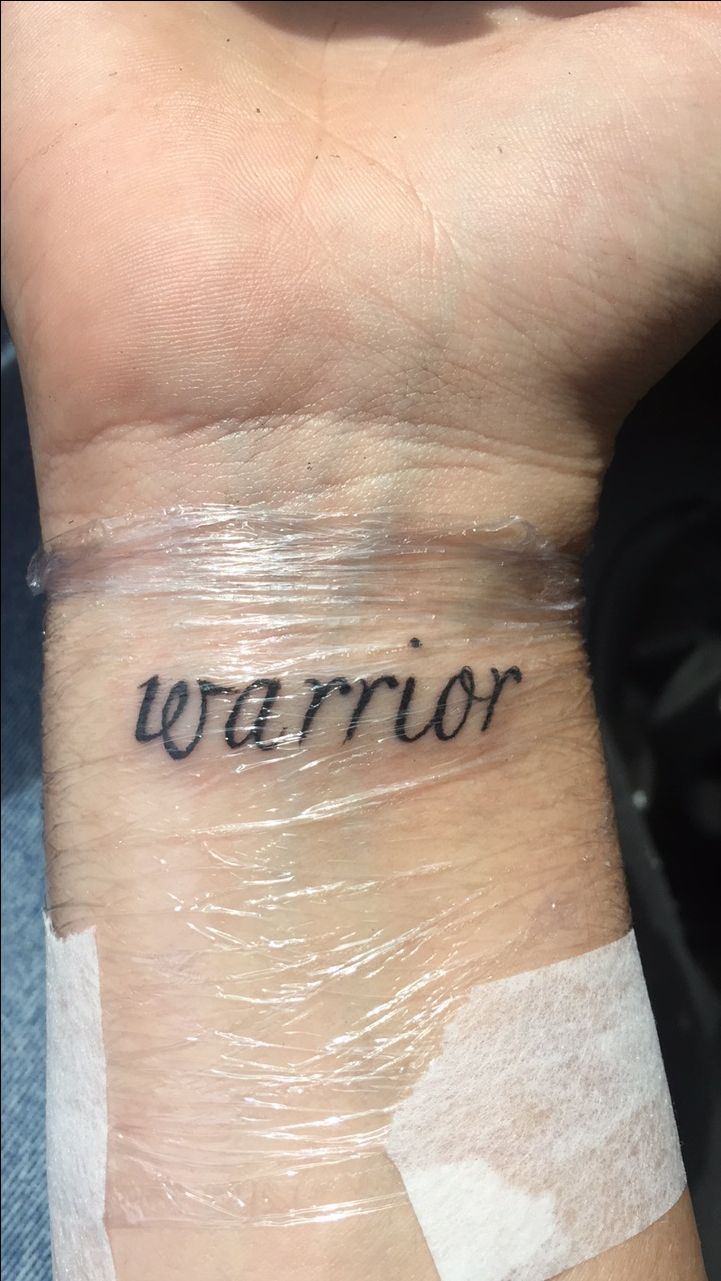 a wrist tattoo with the word warrior written on it