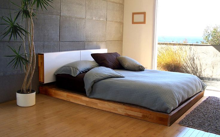 a bed sitting on top of a hard wood floor next to a tall potted plant