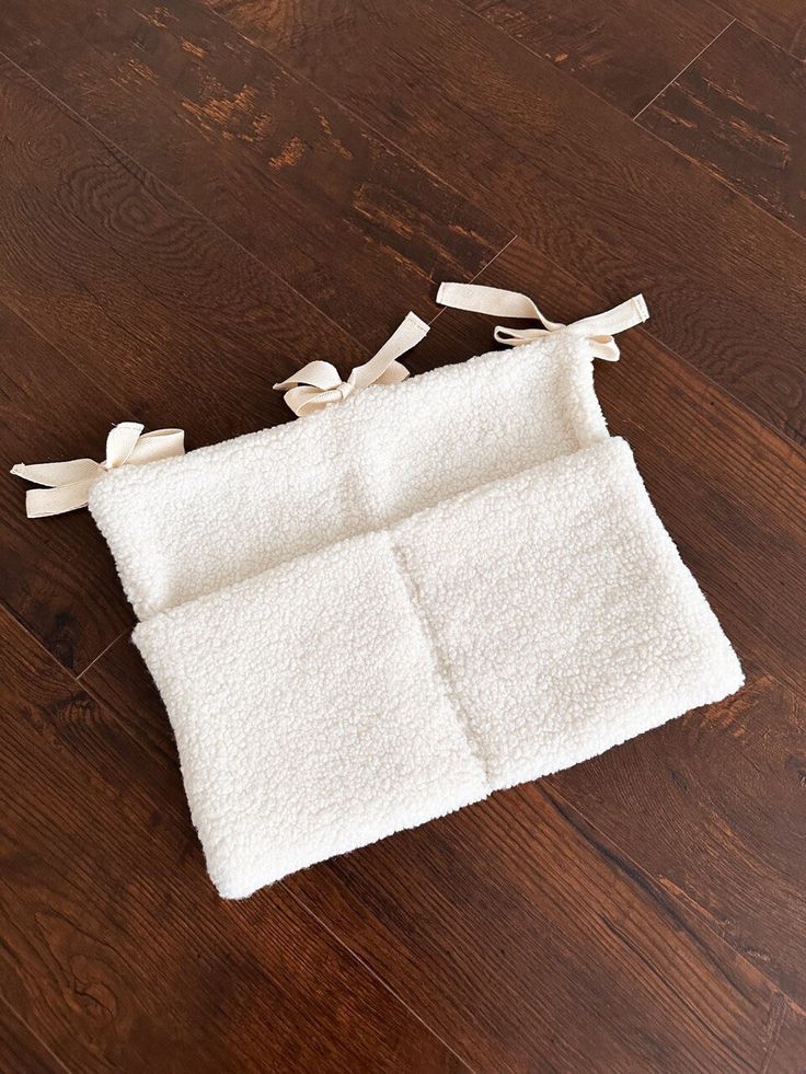 a white towel with bows on it laying on a wooden floor next to a pair of scissors