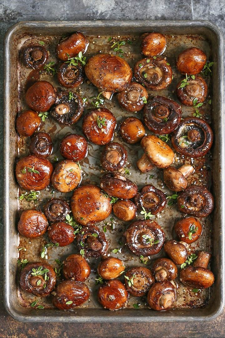 a baking pan filled with cooked mushrooms and garnished with herbs