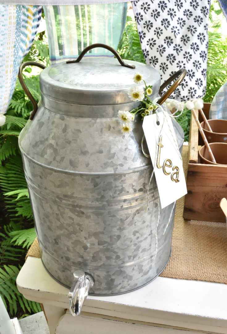 a large metal bucket sitting on top of a table next to a potted plant