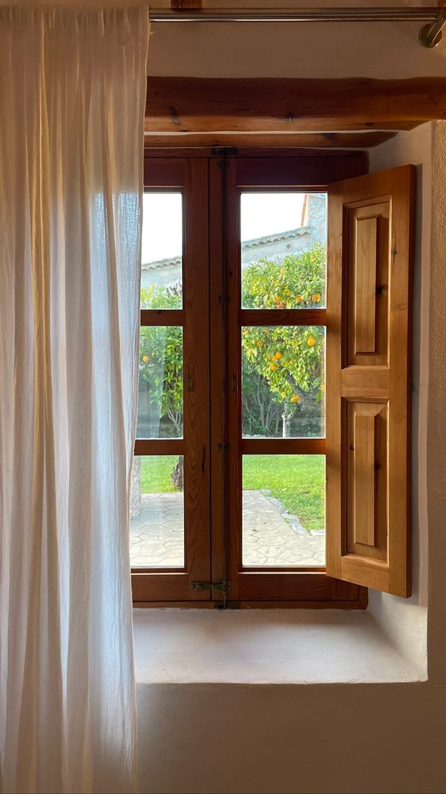 an open window with white curtains in front of it