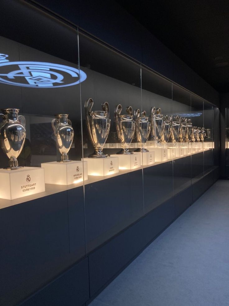 the trophies are lined up on display in front of glass walls that show their logos