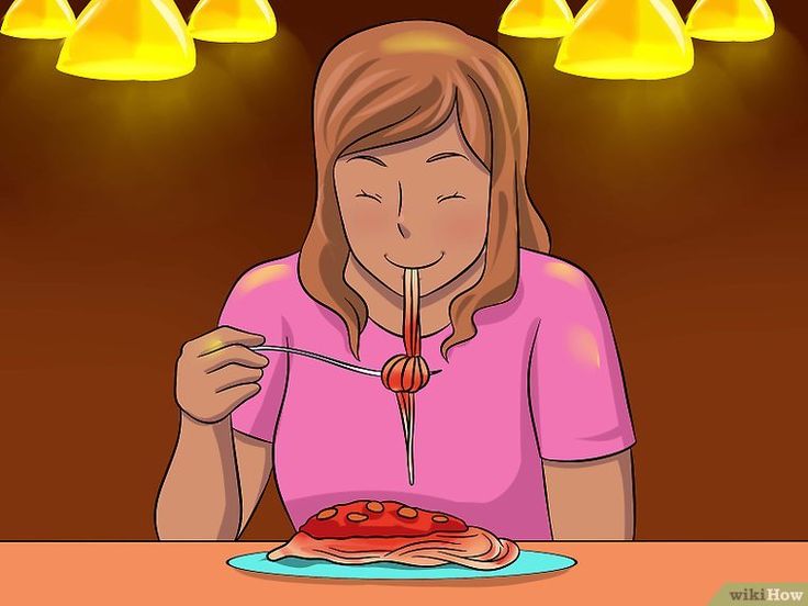 a woman eating pizza at a table in front of yellow lights with her eyes closed