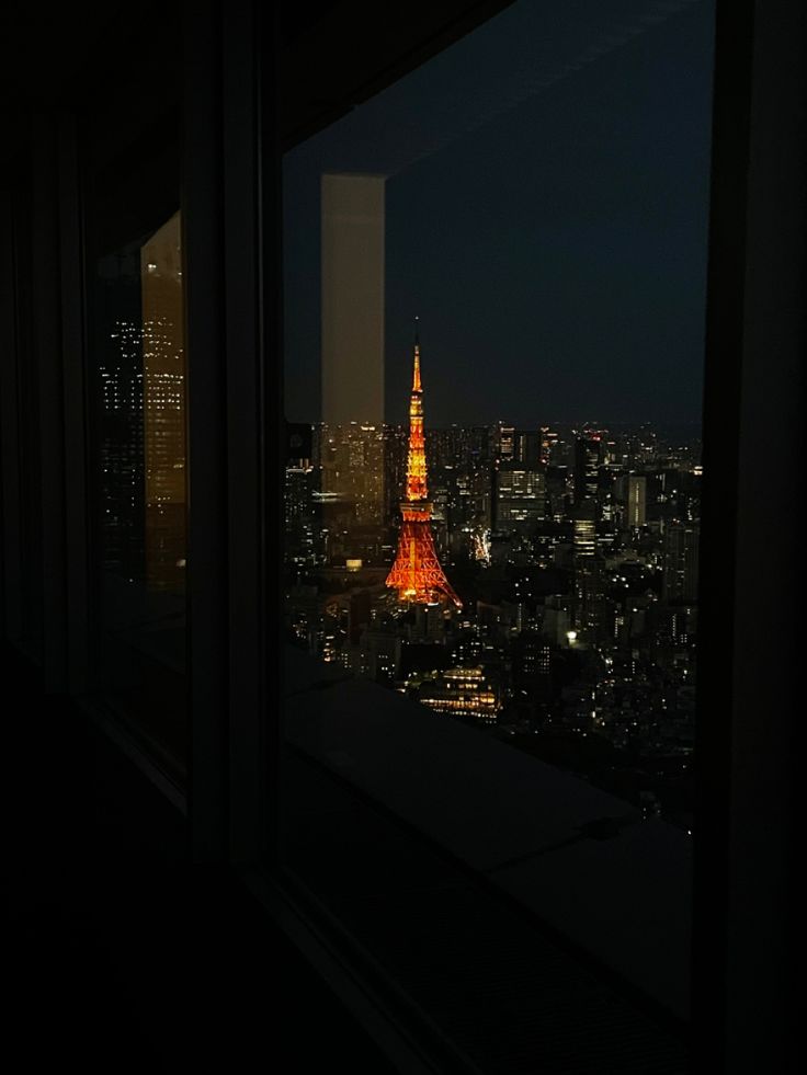 the eiffel tower is lit up in red and yellow at night, as seen from an apartment window