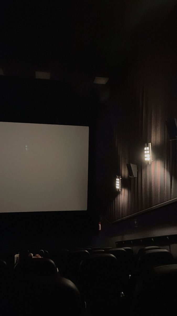 an empty movie theater with people sitting in the seats and one person standing on the stage