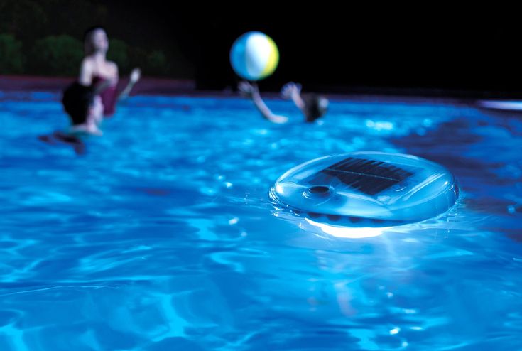 two people are in the pool playing with a ball and a water pumper that is floating on top of it