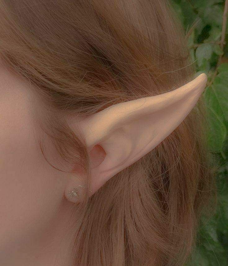 a close up of a woman's ear with long, curved ears and nose piercings