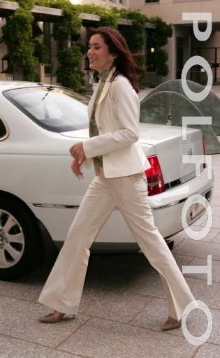 a woman walking across a street next to a white car