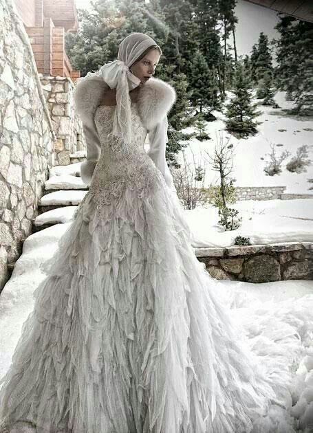 a woman in a long white dress standing on snow covered ground