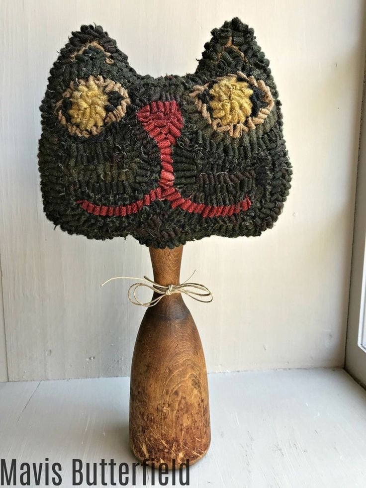 a crocheted cat hat sitting on top of a wooden stand next to a window