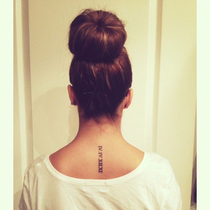 the back of a woman's head with a tattoo on her neck and behind her ear