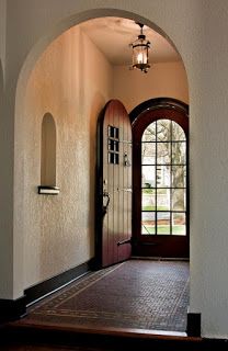 an arched doorway leading to a large entryway with a door in the center and two windows on either side