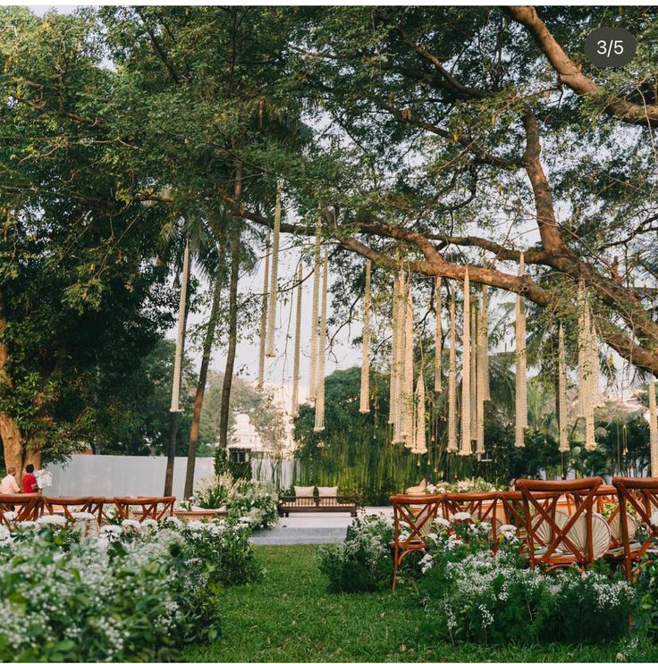 an outdoor wedding venue with wooden benches and tables surrounded by greenery in the foreground