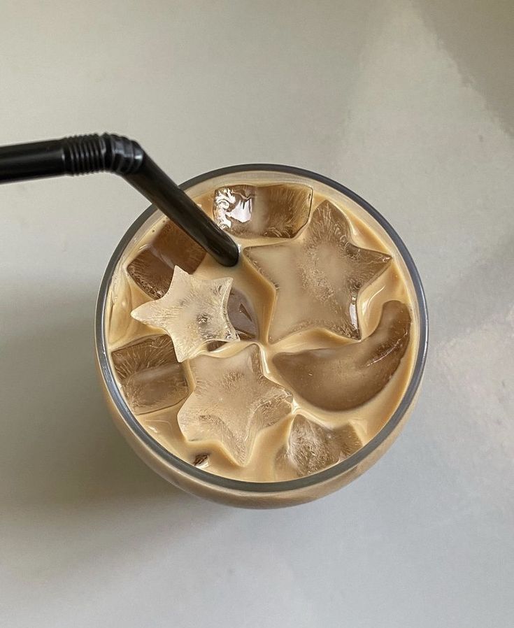 an iced drink with ice cubes and a black plastic straw is on the table