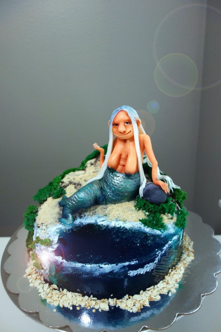 there is a cake that looks like a mermaid sitting on top of the ocean waves