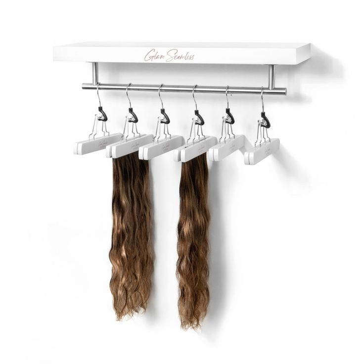 two long brown hair hanging from a white coat rack with clips attached to it's sides