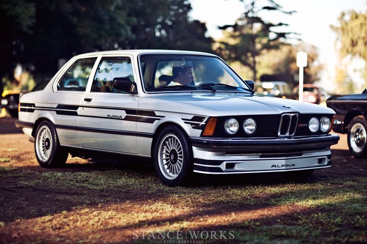 an old bmw is parked in the grass