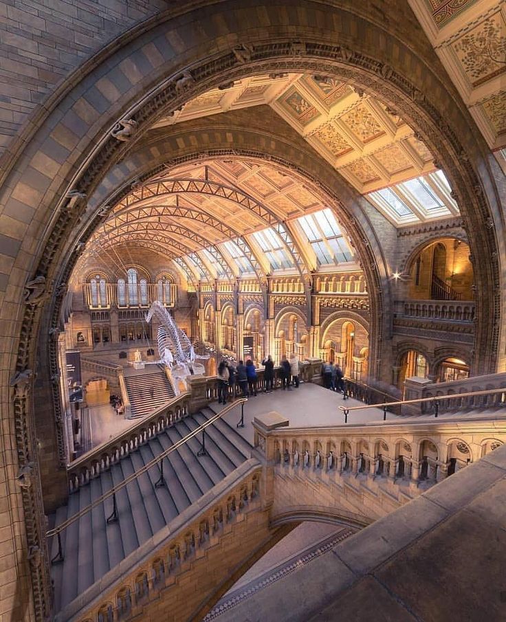 people are walking up and down the escalator in an old building with arched ceilings