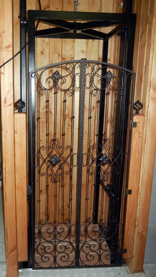 an iron gate in the corner of a wooden room with tile flooring and walls