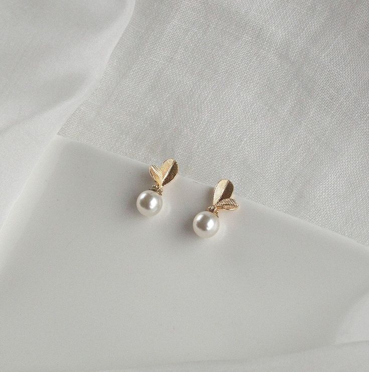 The Lucia earrings are the perfect example when 'Less is more'. They are small but incredibly charming and beautiful. Materials: - 18k gold plated nickel free brass - Pearl Weight per unit: - 2 gramms Measurements: - Length 2 cm - Width 0.8 cm All our creations are carefully packed in a beautifull gift box. Please contact us if you would like to add a gift note or for any other requests. Please be aware that estimated delivery dates do not consider eventual customs delays. Bridesmaid Earrings Gold Simple, Bridal Drop Earrings, Drop Earrings Pearl, Simple Gold Earrings, Pearl Drop Earrings Gold, Bride Party, New Gold Jewellery Designs, Bridesmaid Earrings Gold, Bridal Earrings Drop