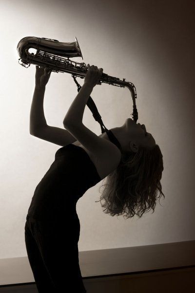 a woman is playing the saxophone in black and white