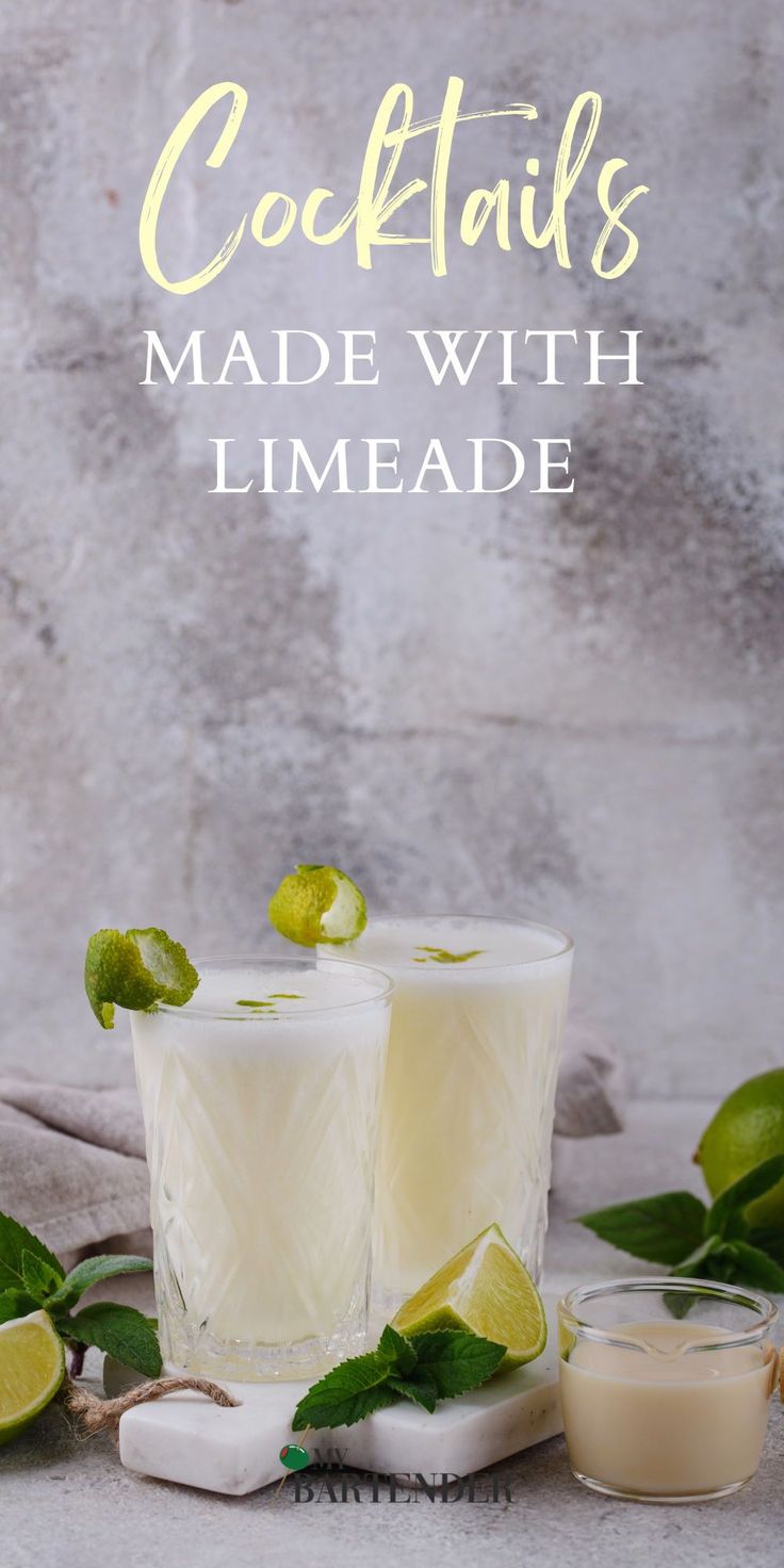 two glasses filled with limeade sitting on top of a table next to sliced limes