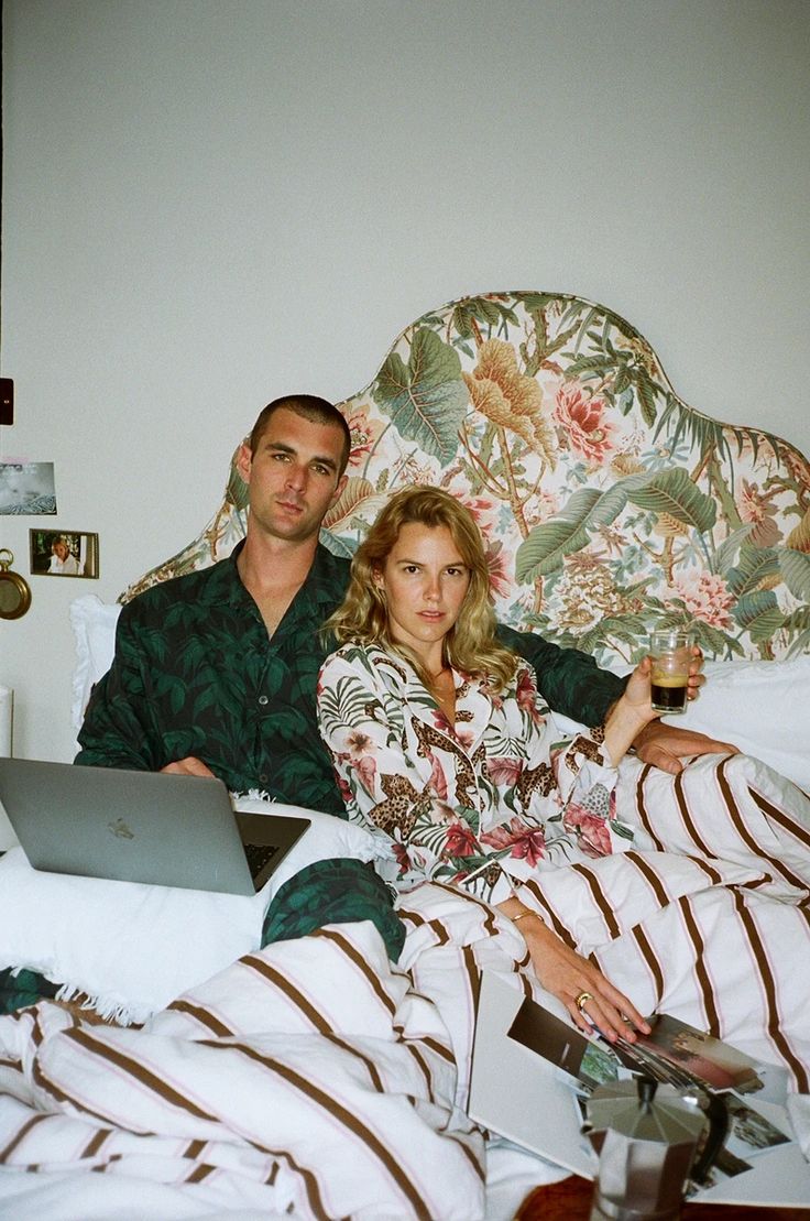 a man and woman laying in bed with laptops