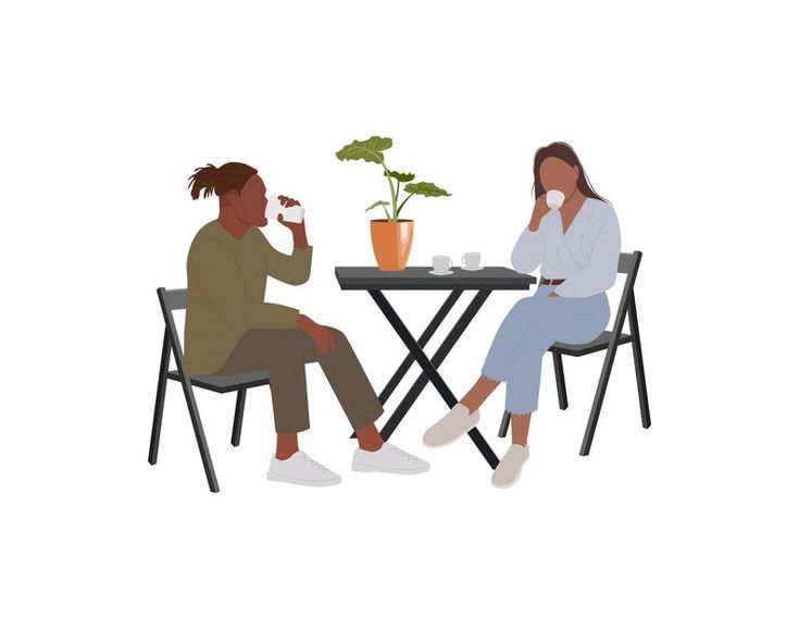 two people sitting at a table with plants on the table and one person eating food