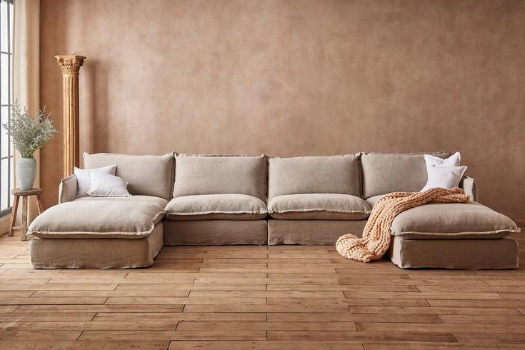 a living room with wooden floors and a beige couch on the floor next to a large window