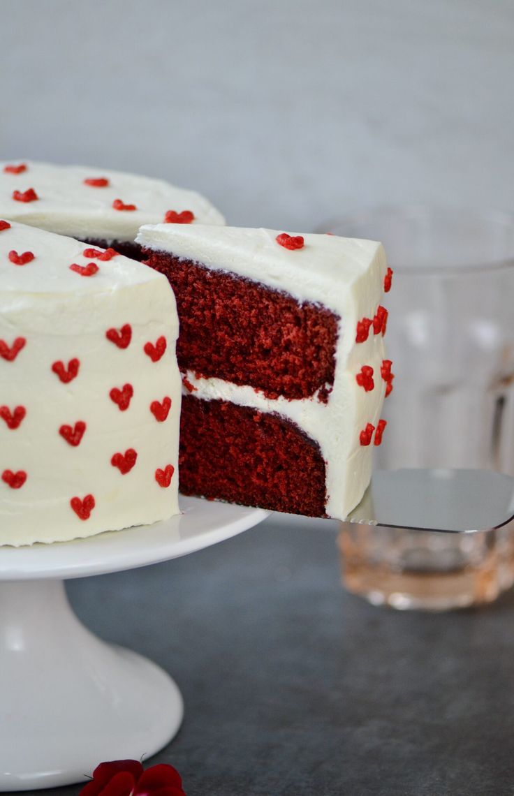 a red velvet cake with white frosting and hearts on the outside is cut in half