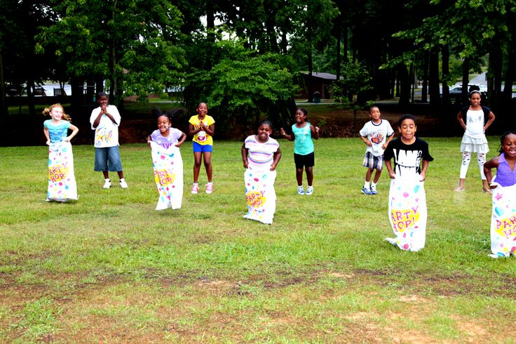 a group of young children standing on top of a lush green field next to each other