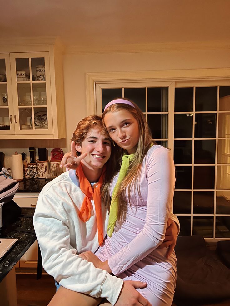 two young people are posing for a photo in the kitchen with their arms around each other