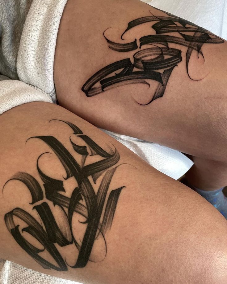 two black ink tattoos on the legs of someone's leg, both with letters