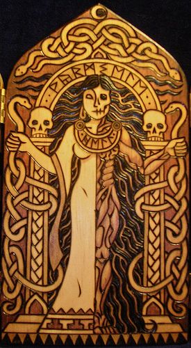 an intricate wooden plaque with a woman holding two skulls