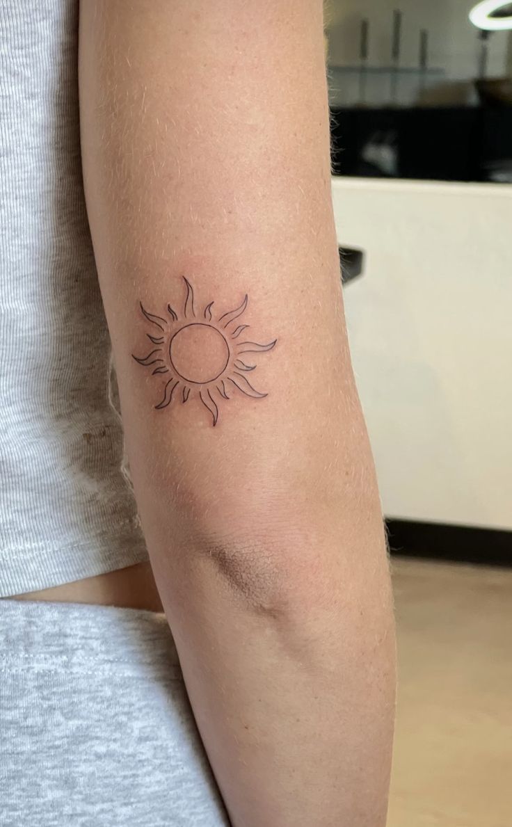 a woman's arm with a tattoo on it that has a sun in the middle