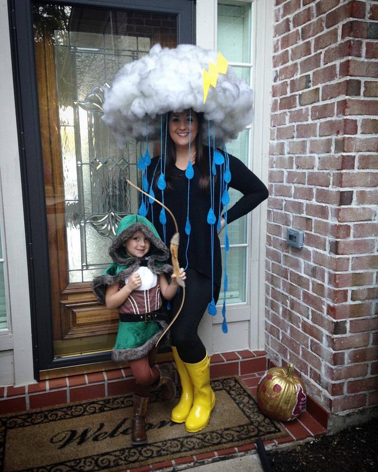 a woman standing next to a child wearing rain boots and holding an umbrella over her head