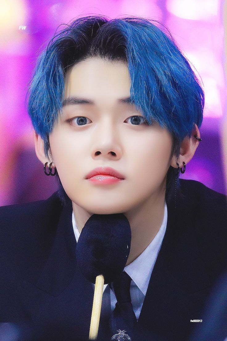 a young man with blue hair wearing a suit and holding a microphone in front of his face