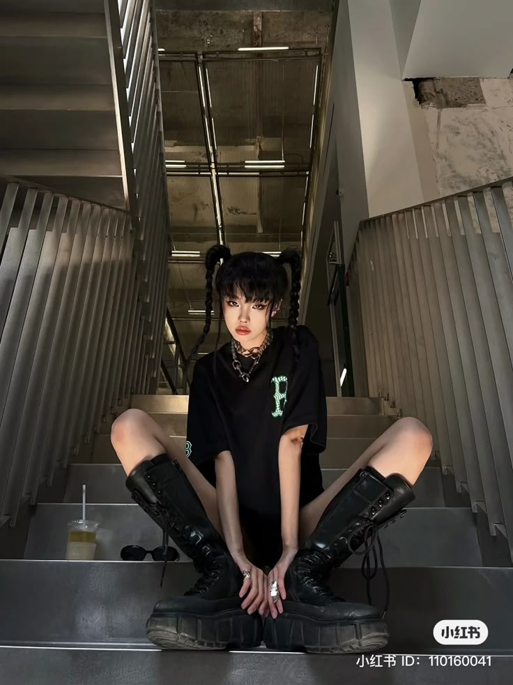 a woman sitting on the ground with her legs crossed in front of her face and wearing black boots