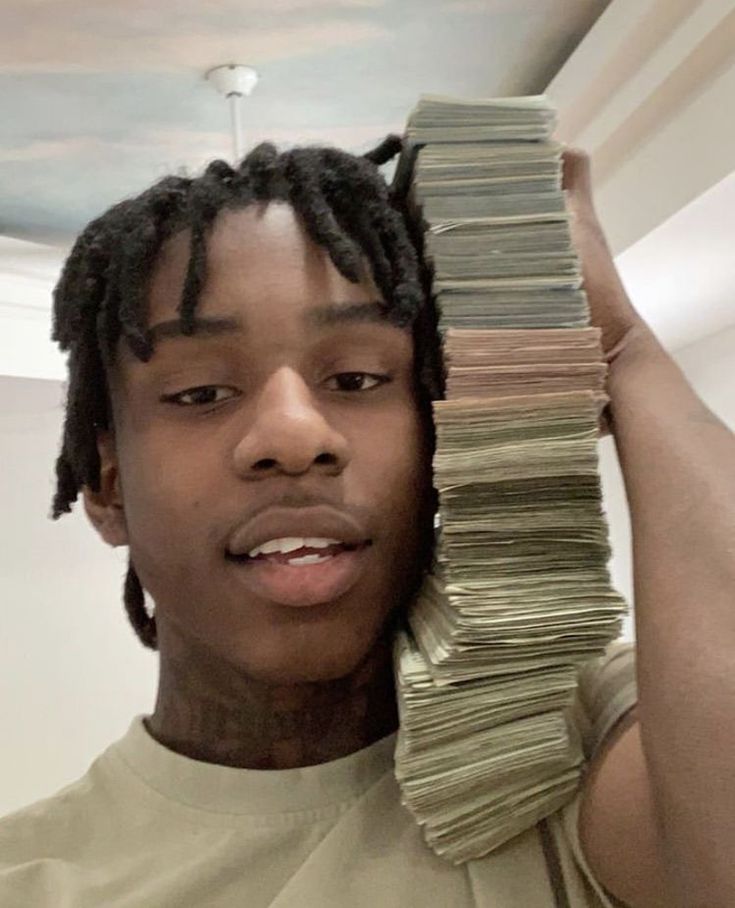 a young man holding stacks of money in front of his face