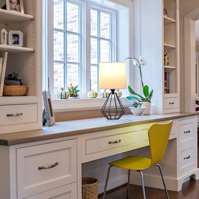 a kitchen with white cabinets, yellow chairs and a large window above the countertop