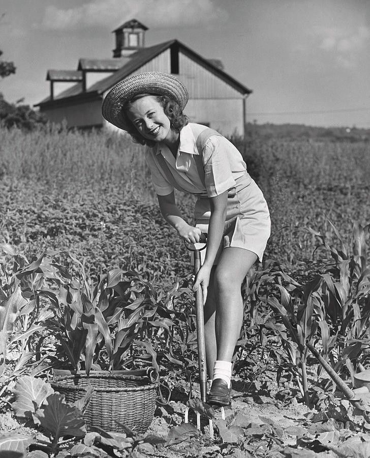 an old black and white photo of a woman in a field with a rakel