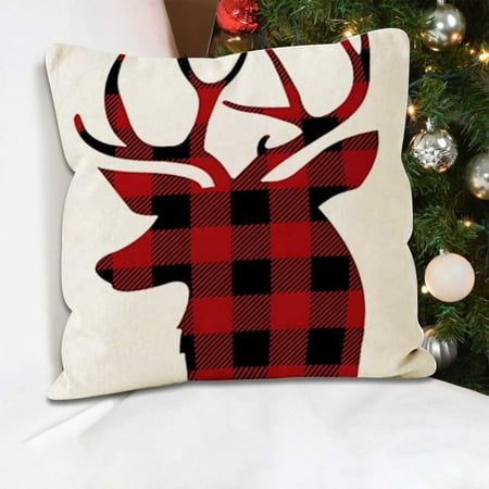 a red and black plaid deer pillow sitting on top of a bed next to a christmas tree